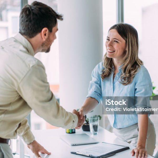 Business people shaking hands in the office. Photo of one cheerful businessman and one happy businesswoman handshaking across the table.